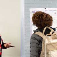 Individual talking to two students